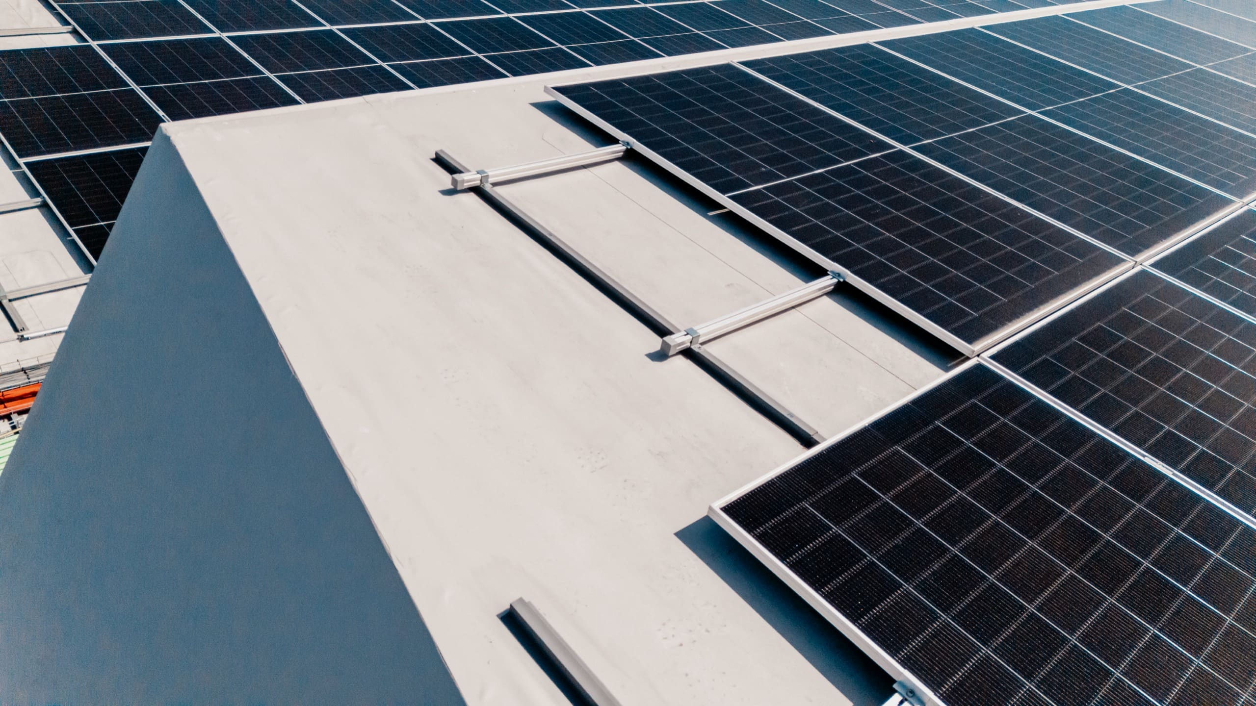 Vue aérienne rapprochée de panneaux solaires posés le long d’un shed blanc.
