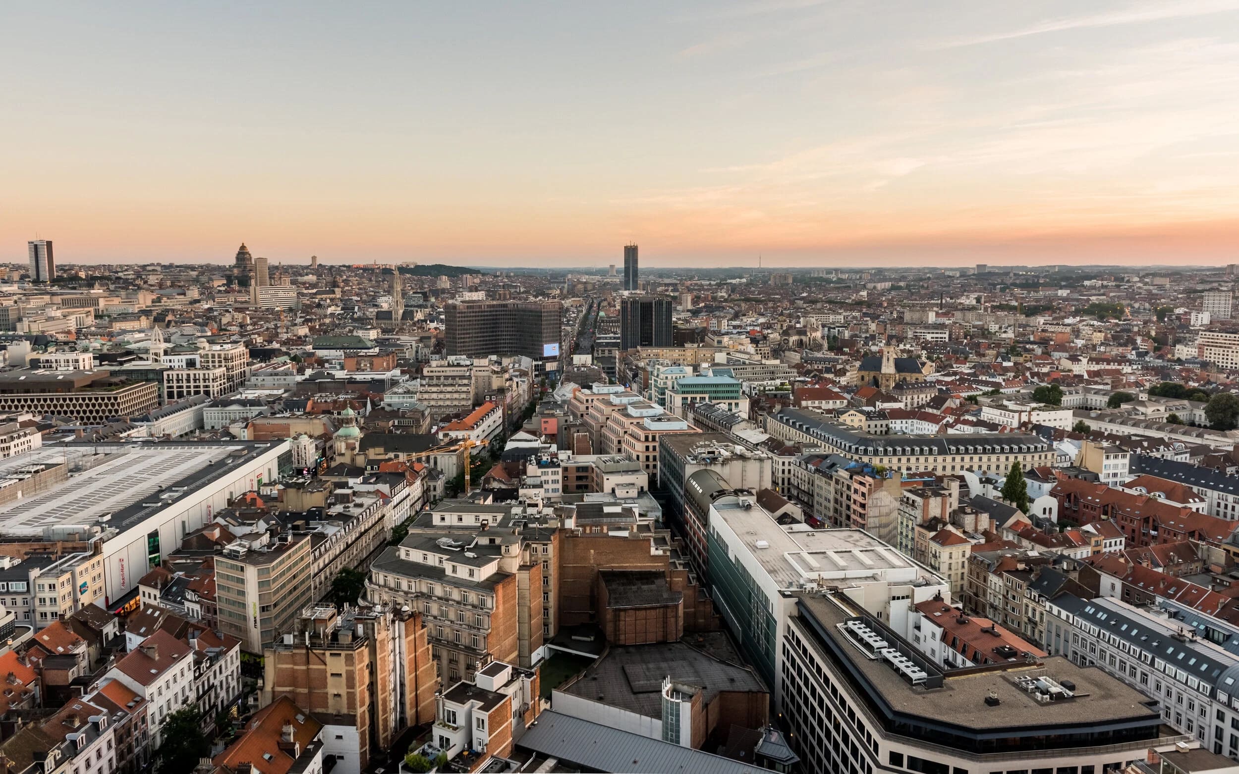Panorama over the rooftops of Brussels at dusk, out to the towers on the horizon.
