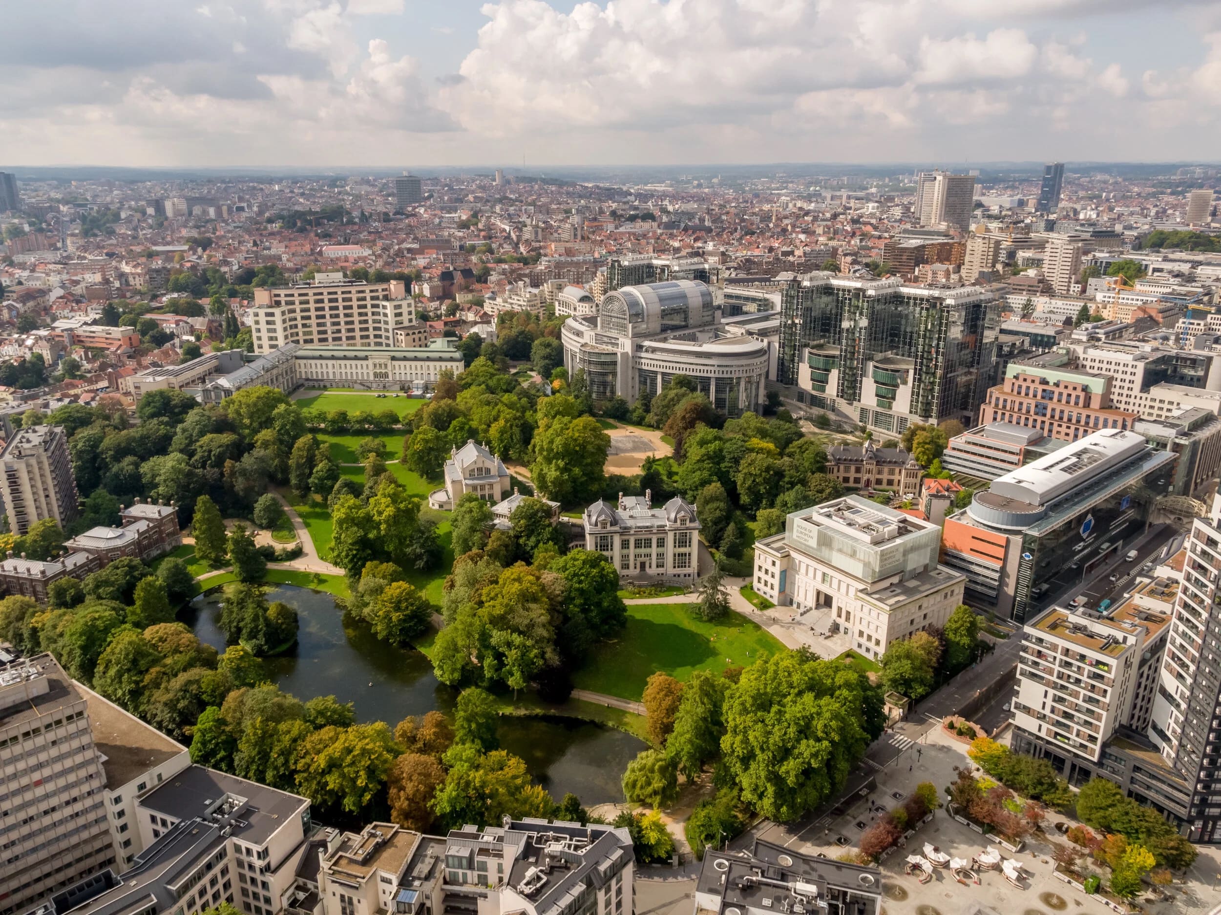 Luchtbeeld van een groot stadspark en de Europese wijk in Brussel onder een bewolkte hemel.