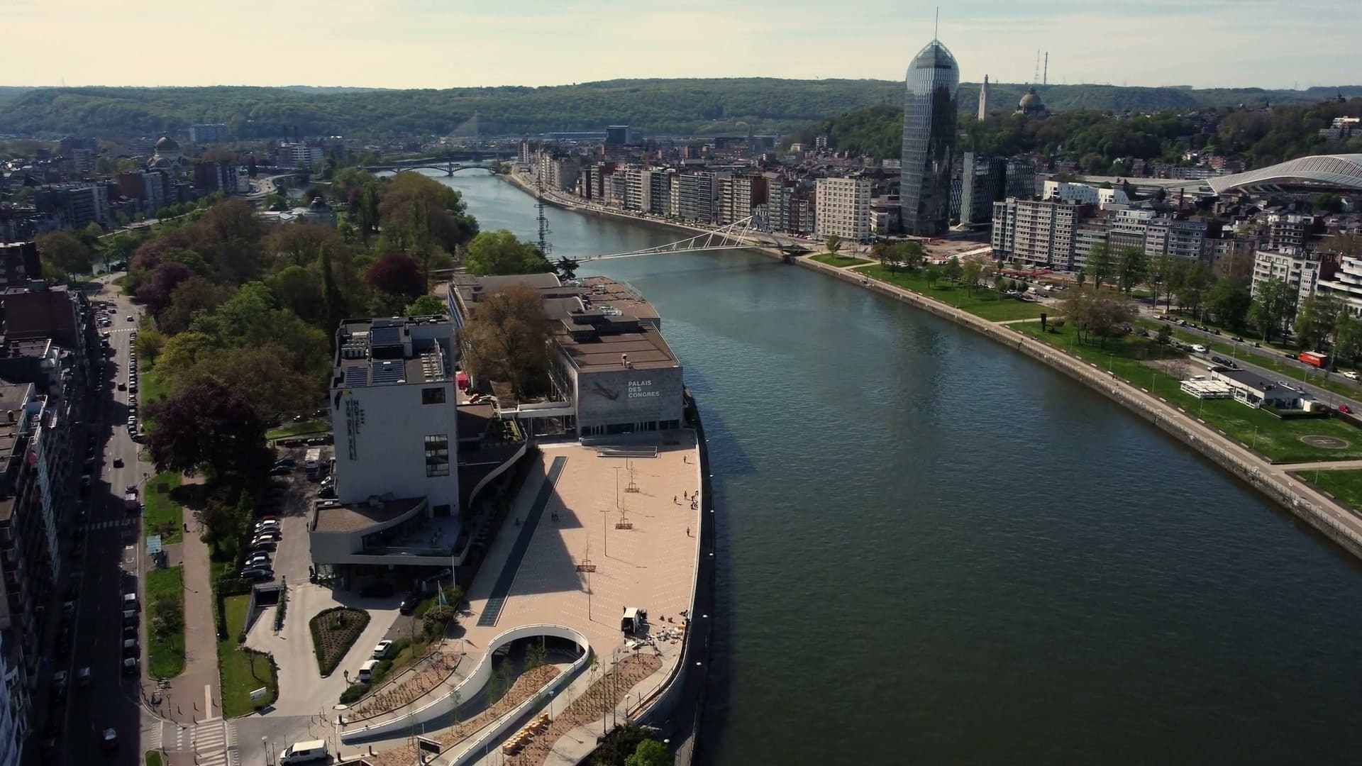 Aerial view of a riverside city with quays and a footbridge, from a corporate film.