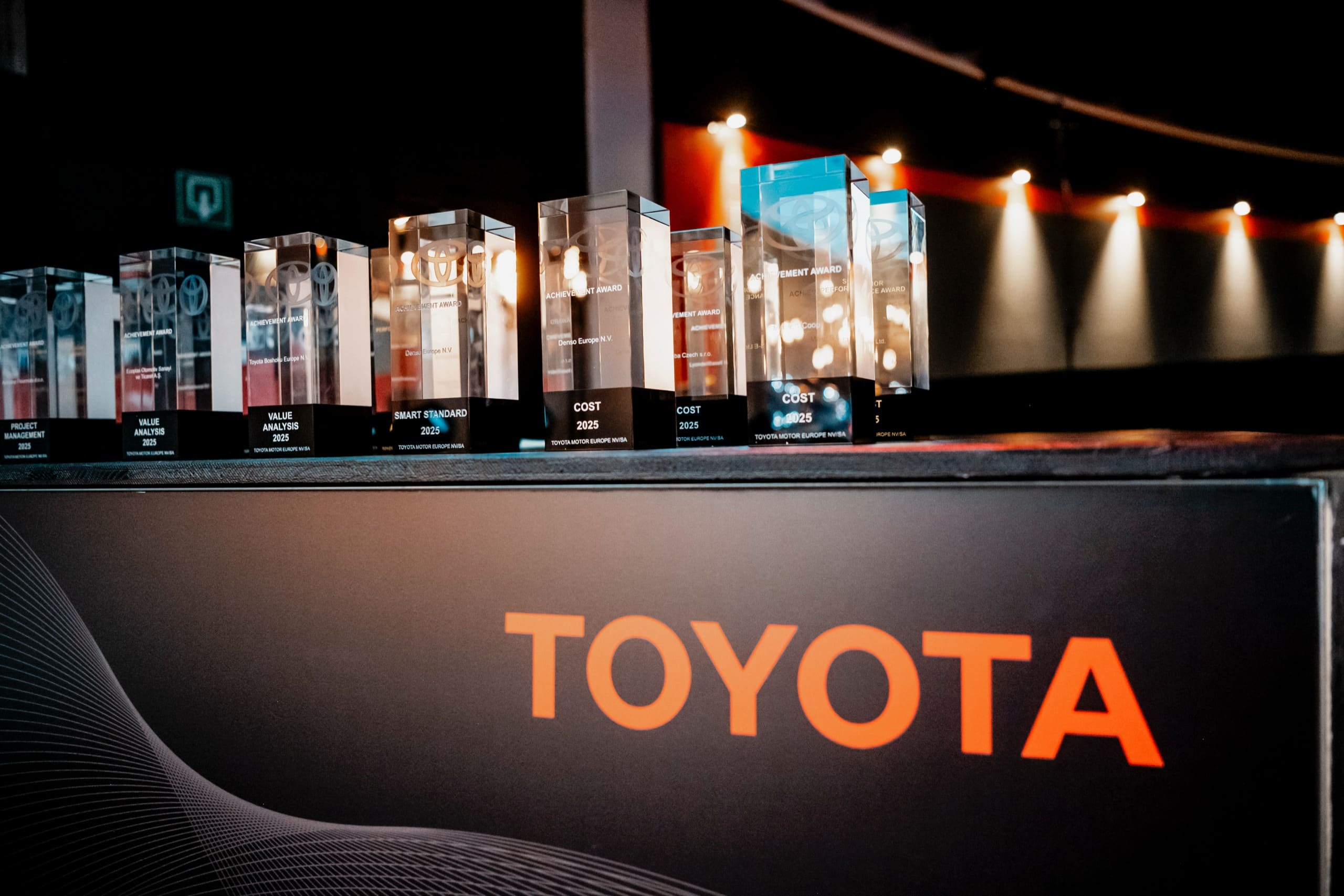 Des trophées en verre alignés sur un comptoir noir marqué Toyota, avant l’arrivée des invités.