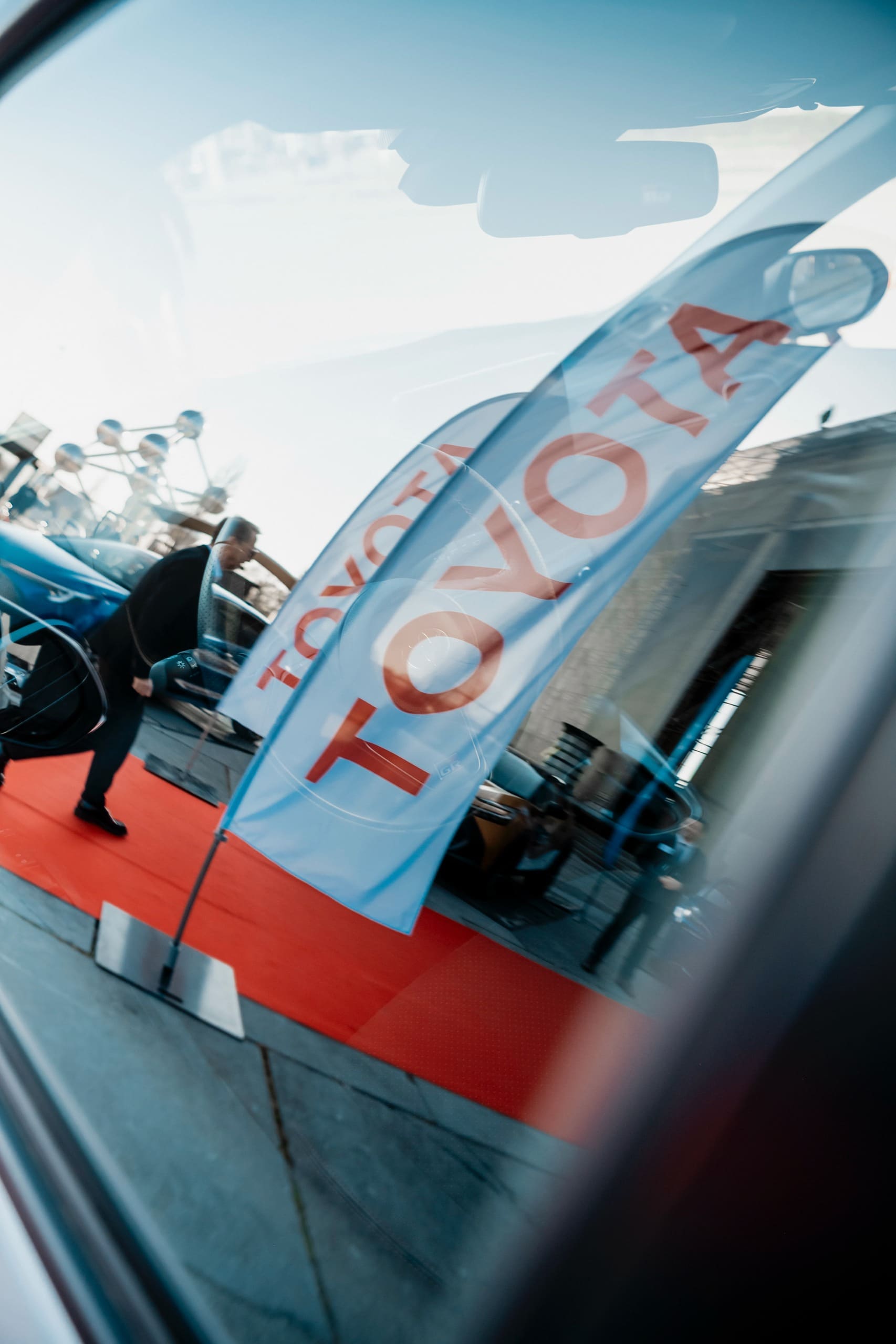 Un drapeau Toyota se reflète dans la carrosserie d’une voiture, à l’entrée.