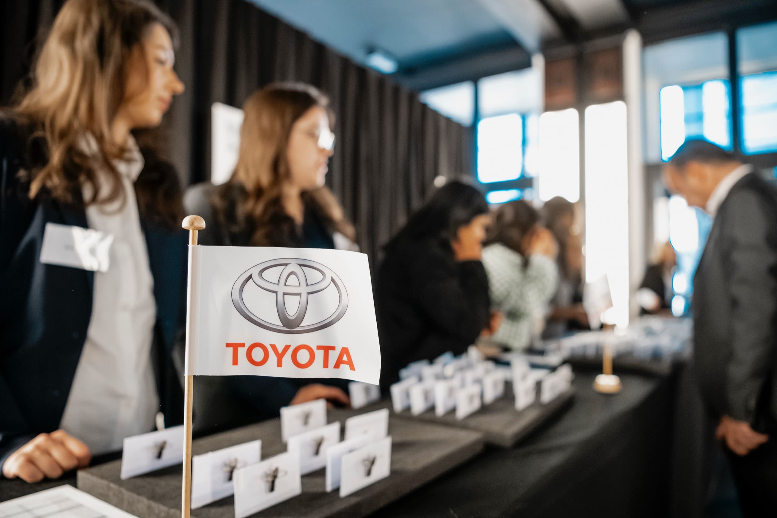 Le comptoir d’accueil : les hôtesses remettent les badges, un petit drapeau Toyota sur la table.