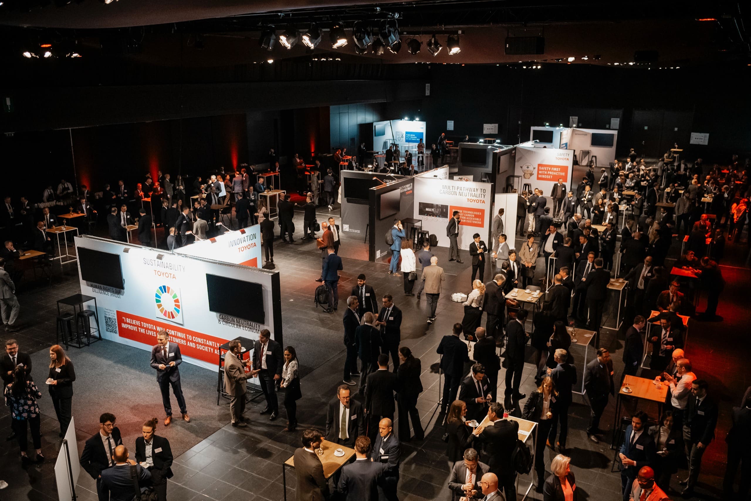 Vue plongeante sur le hall : les stands et la foule des invités.