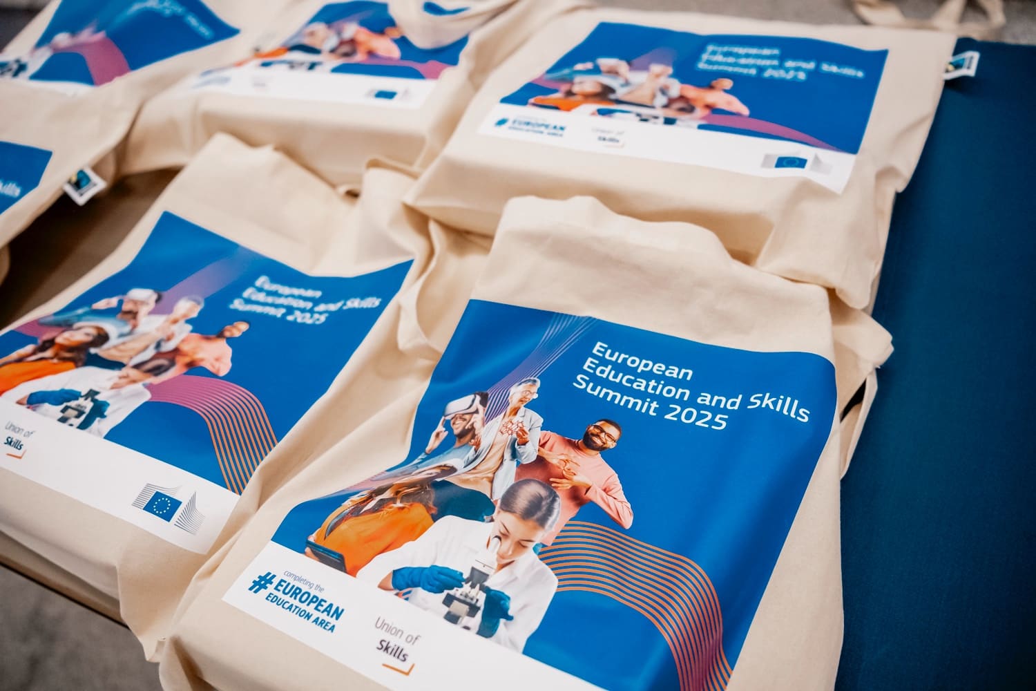 Unbleached canvas tote bags printed in a summit's colours, on a blue table.