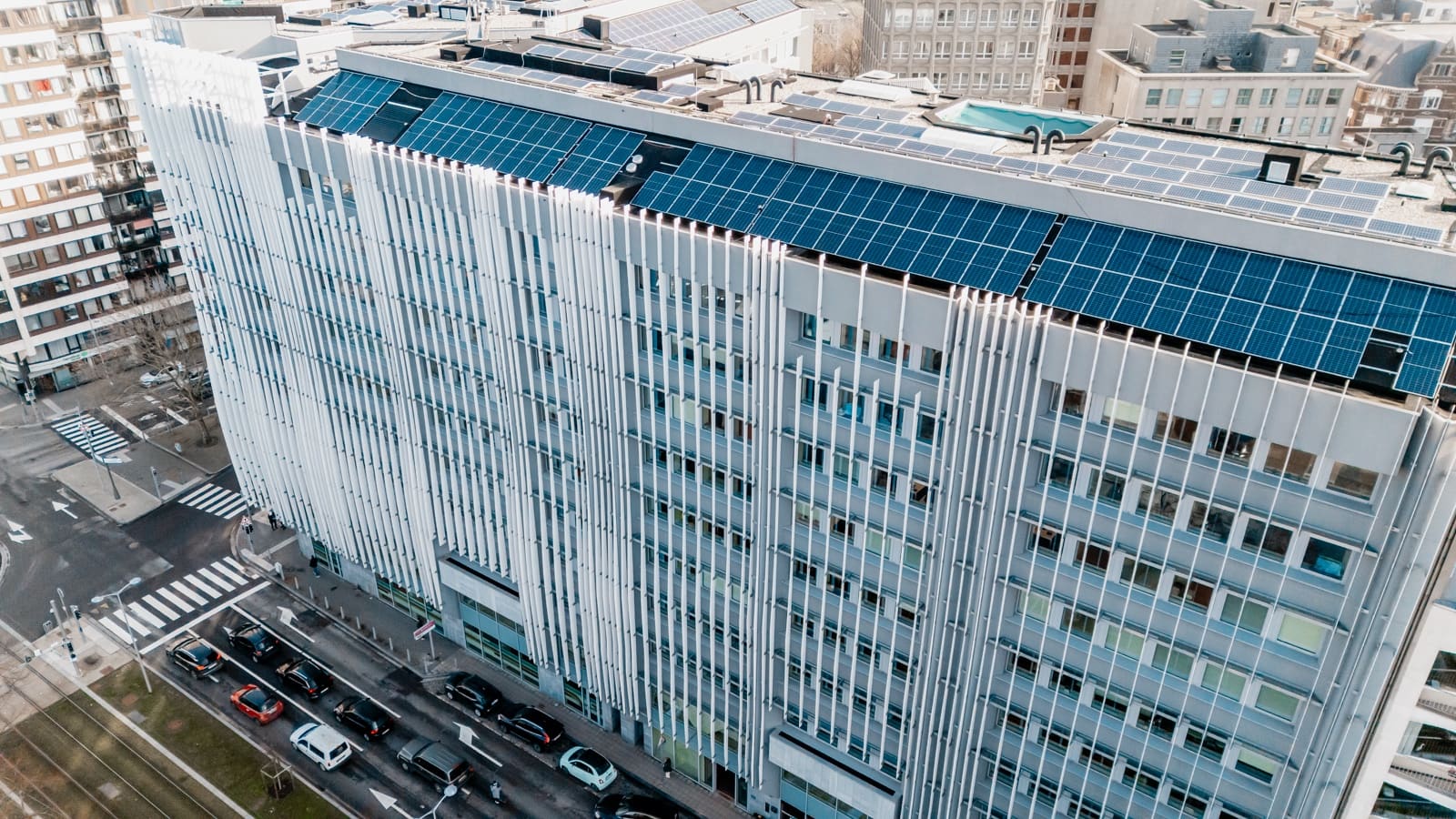 Office building with vertical white fins and a solar roof, seen at an angle.