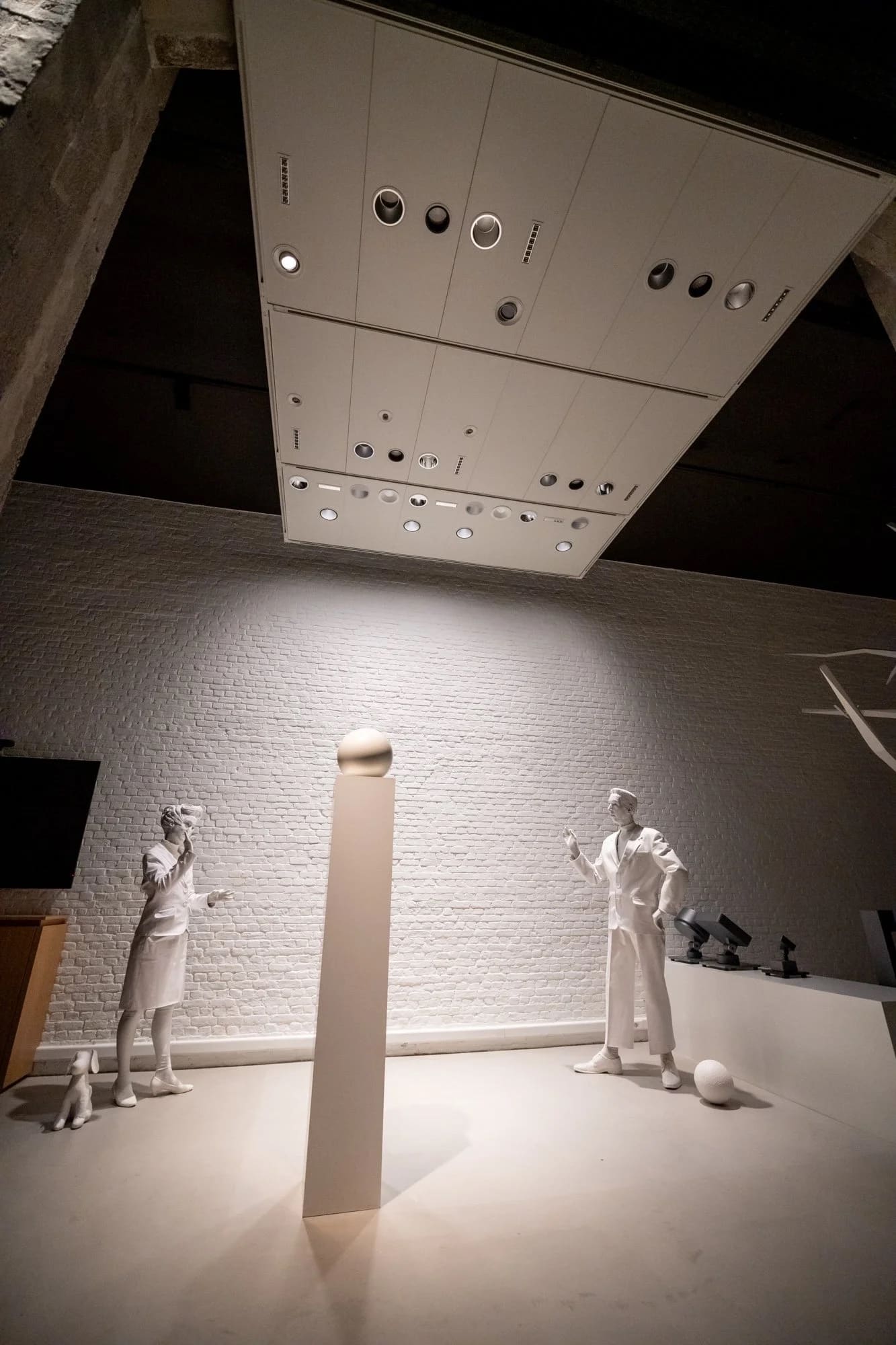 Lichtscenografie: licht geprojecteerd op witte beelden voor een witte bakstenen muur.