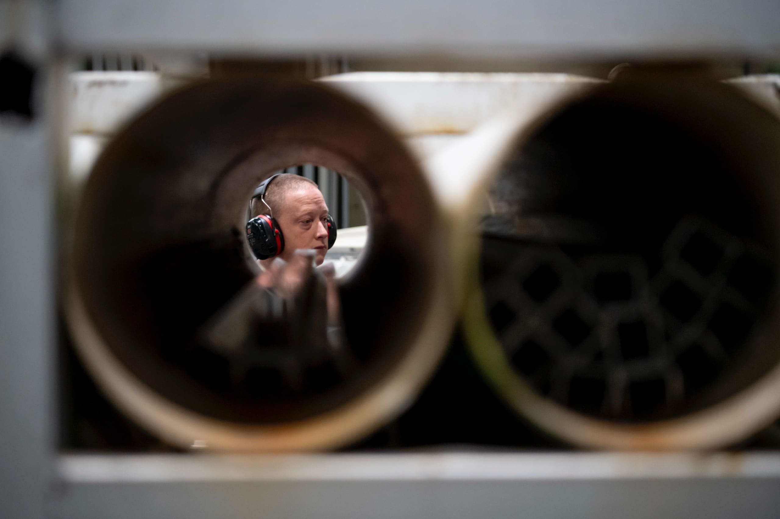Un ouvrier vu à travers les tubes de rangement des profilés.