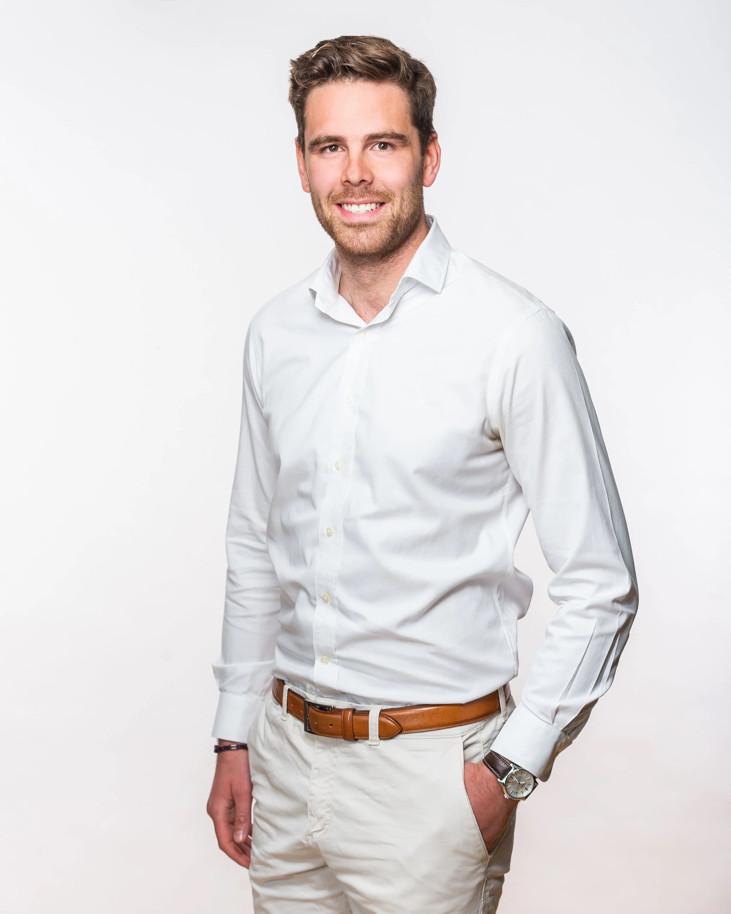 Full-length studio portrait of a smiling man in a white shirt, on a white background.